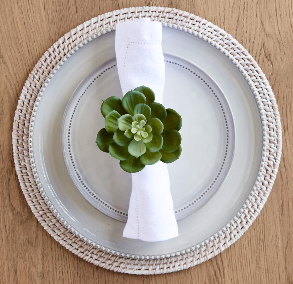 White linen hemstitched napkin with echeveria napkin ring on plate